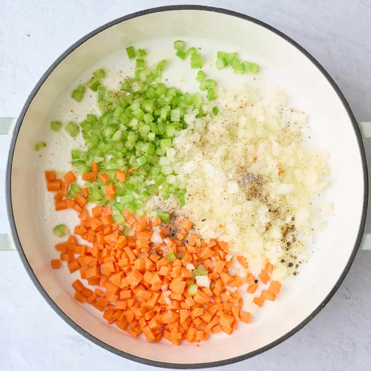 Diced onions, celery, and carrot in pot with seasonings before cooking.