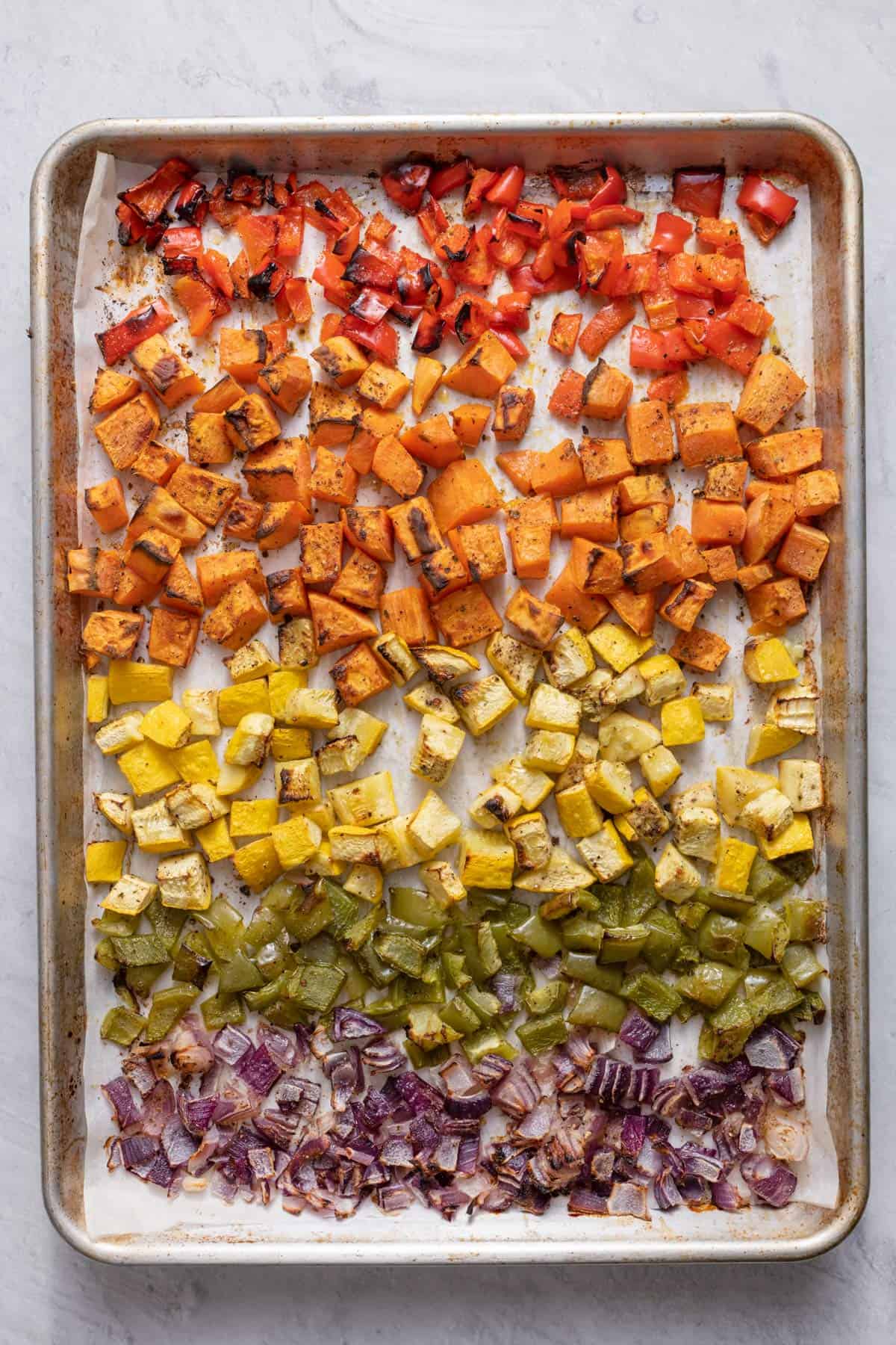 Diced roasted vegetables on a sheet pan after cookiing.