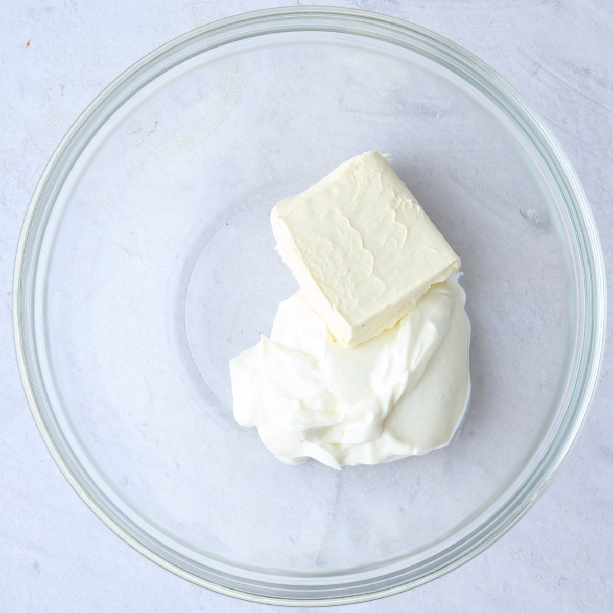 Greek yogurt and cream cheese in a bowl before mixing for dip recipe.