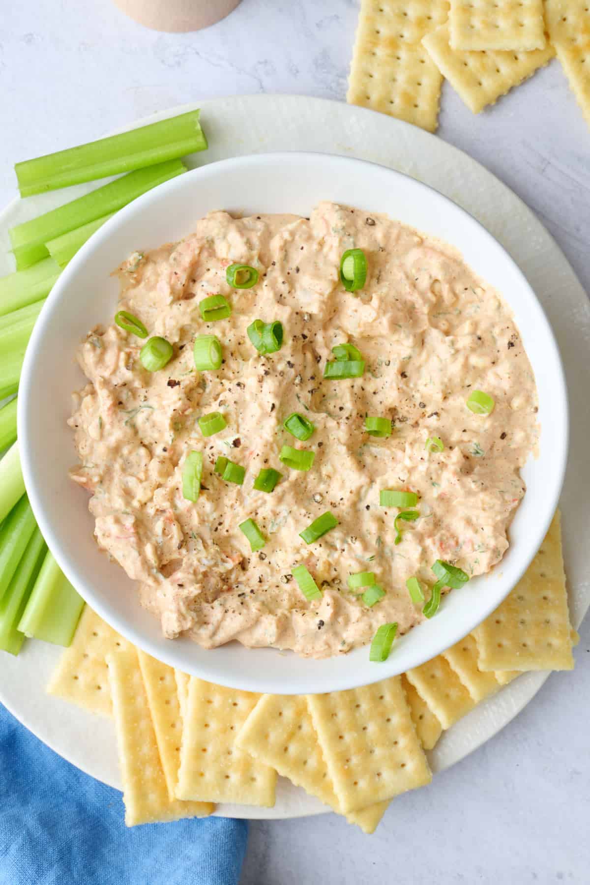 Shrimp dip with cream cheese served in a bowl with crackers and celery for dipping.
