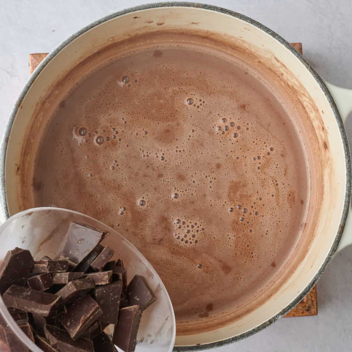 Dairy free dark chocolate chunks being added to almond milk chocolate base in pot.