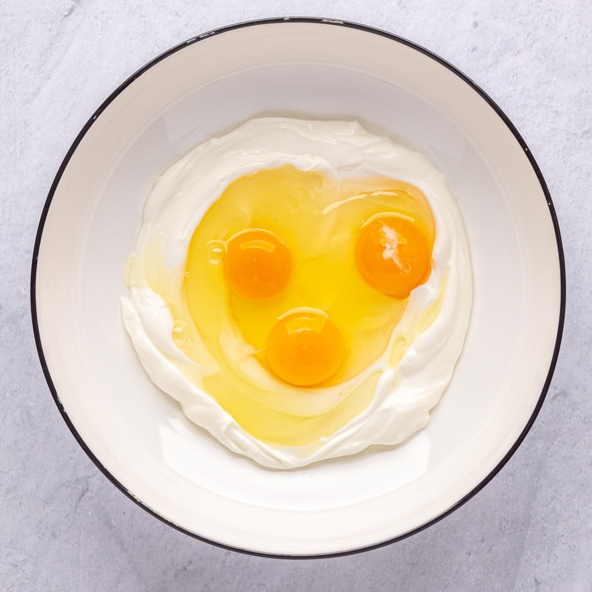 Greek yogurt and eggs in a bowl before mixing.