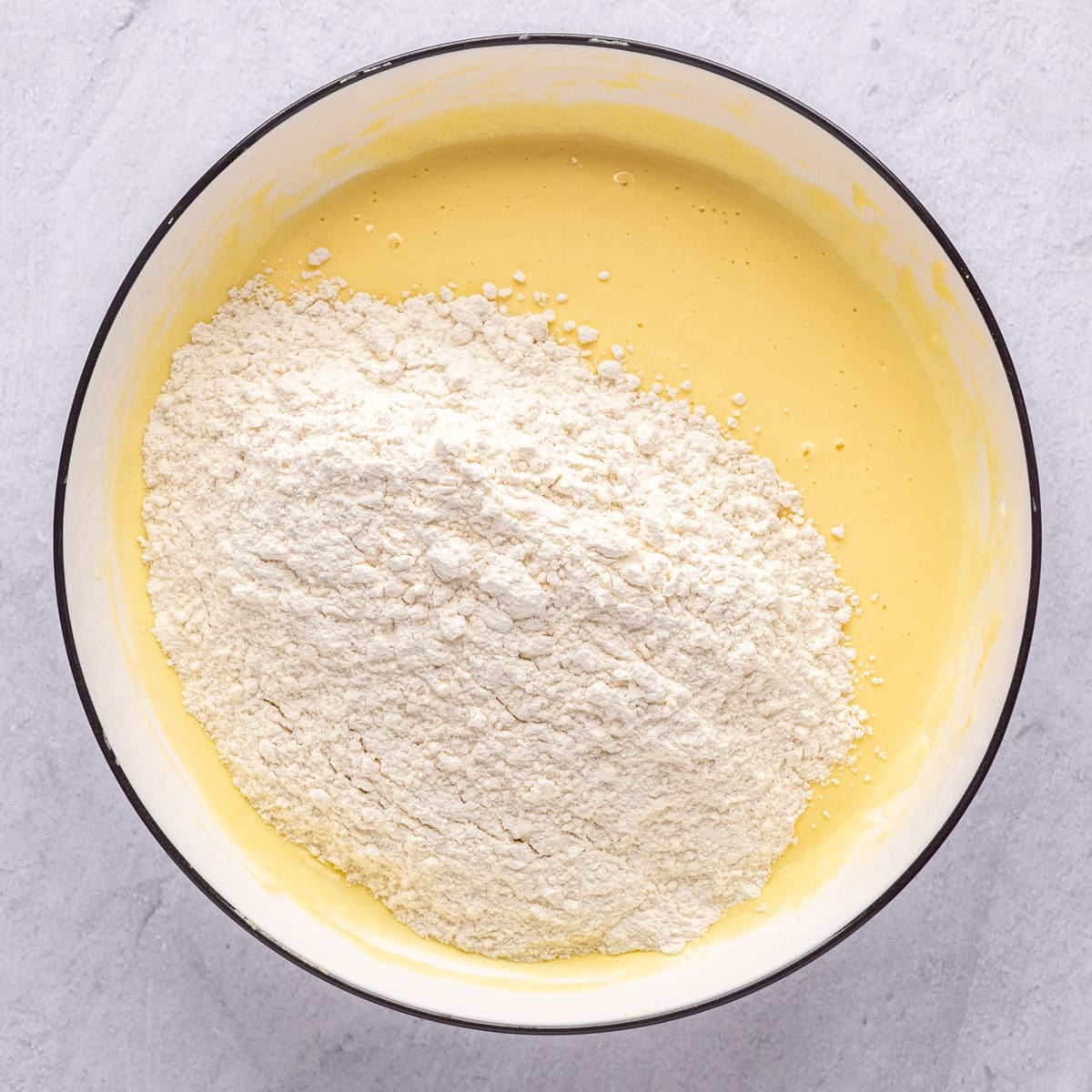 Yogurt and eggs in a bowl after whisking together with dry ingredients on top to the side.