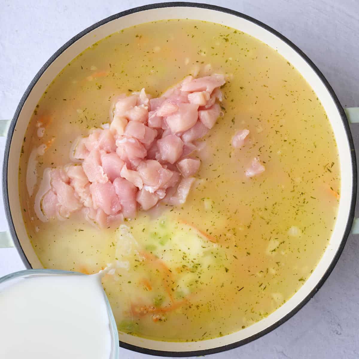 Broth whisked in to cooked veggies with milk and chicken added before stirring.