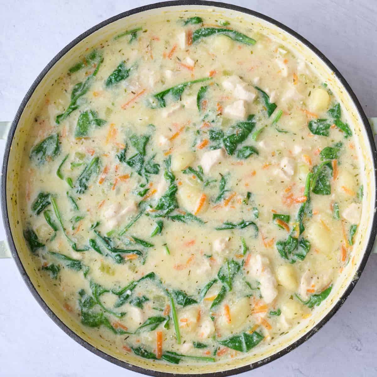 Creamy gnocchi soup with chicken and spinach after wilting.