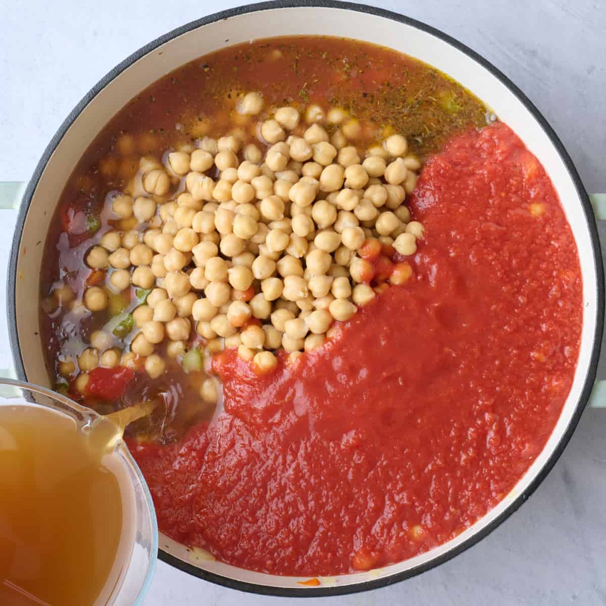 Chickpeas, tomatoes and broth added to pot with soup veggies.