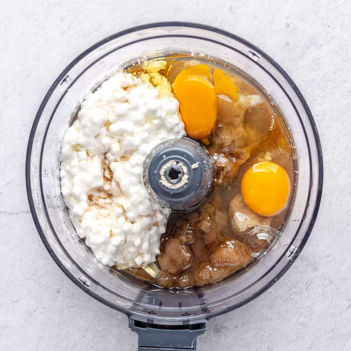 Eggs, cottage cheese, oil, brown sugar, and vanilla extract in a food processor before processing.
