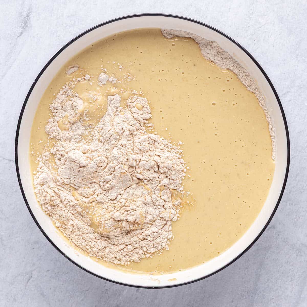 Wet mixture added into bowl with dry ingredients before folding together.