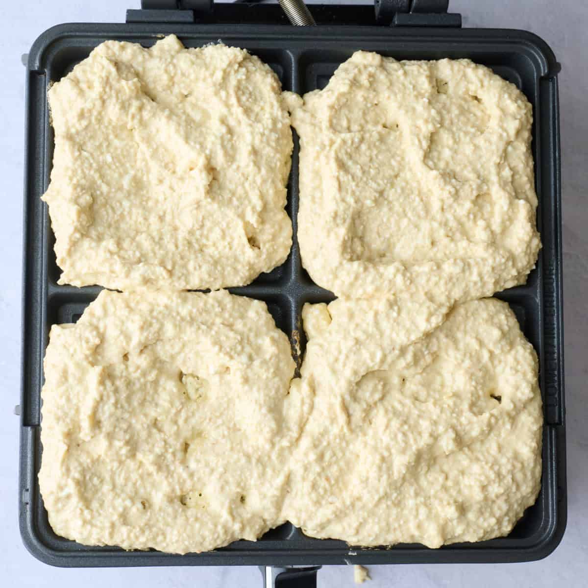 Cottage cheese oat waffle batter added to a waffle iron before cooking.