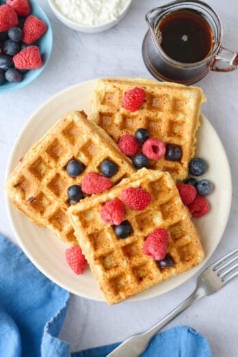 Best high protein waffles made with cottage cheese, oats and eggs on a plate served with fresh mixed berries on top.