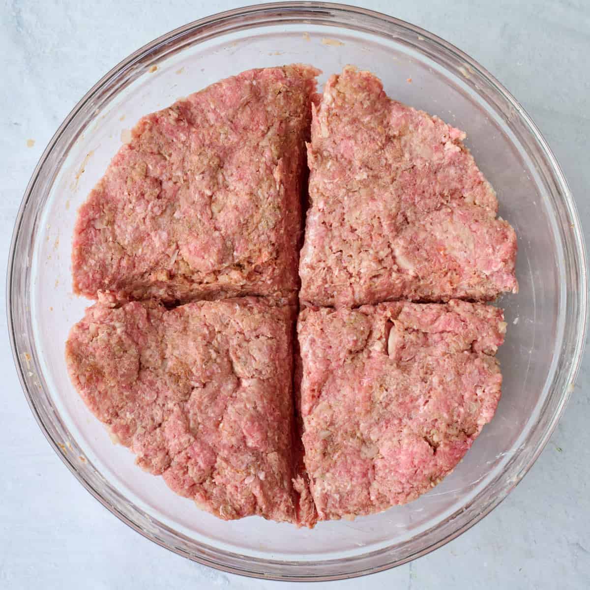 After ground beef mixture is well combined and divided into four equal portions in the bowl.