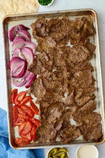 Homemade doner kebab recipe on a sheet pan with roasted tomatoes and onions.