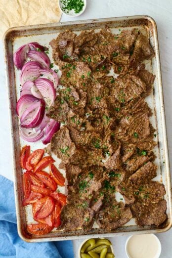 Homemade doner kebab recipe on a sheet pan with roasted tomatoes and onions.