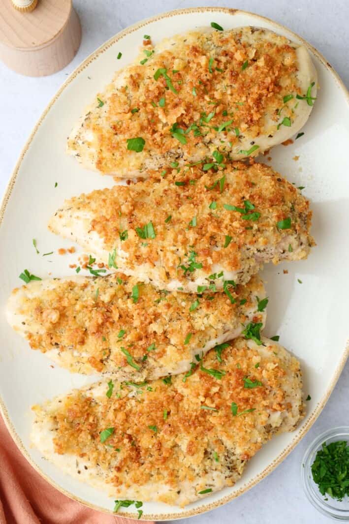 Best garlic parmesan chicken recipe on a platter garnished with chopped parsley.