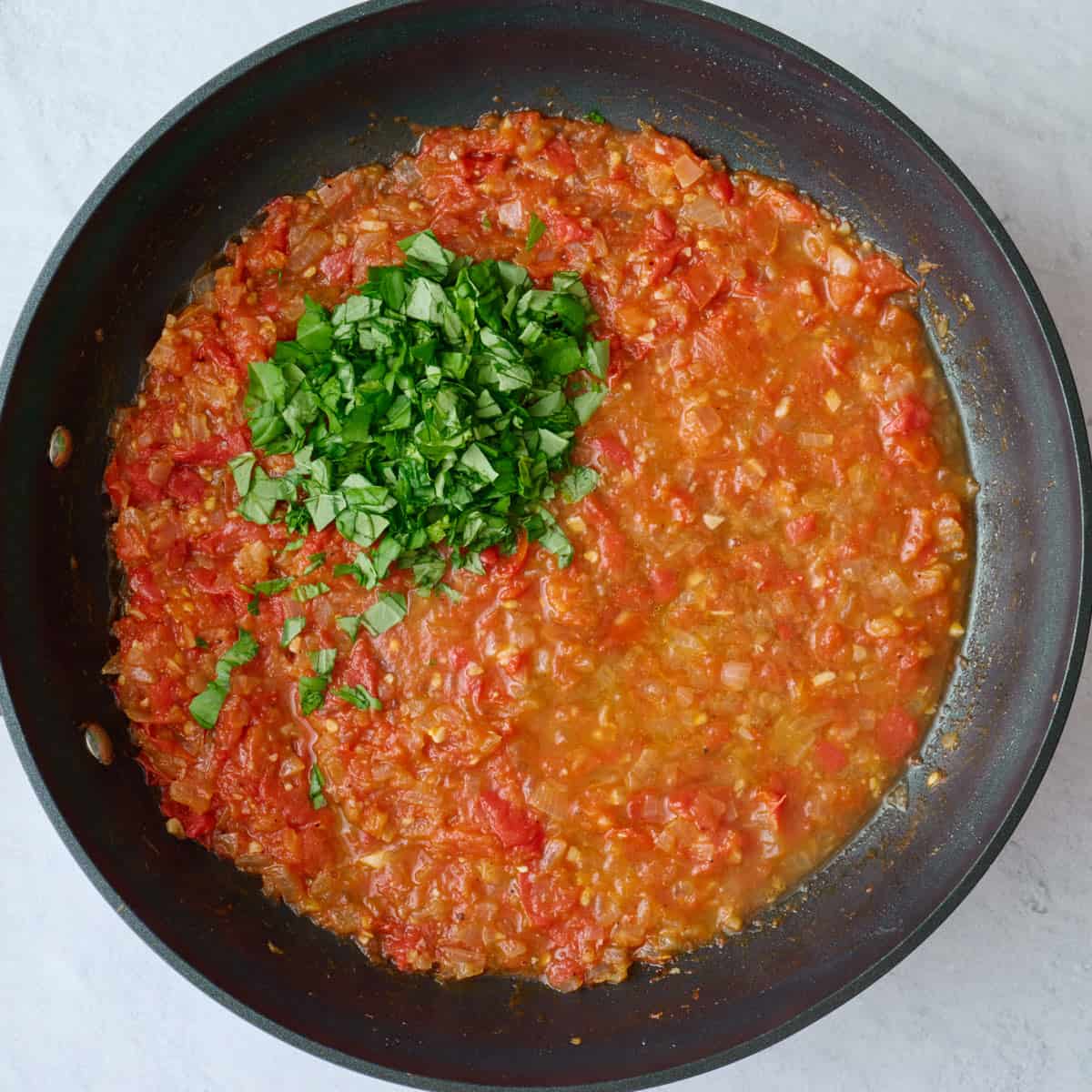 After simmering tomatoes with chopped basil and pasta water added.