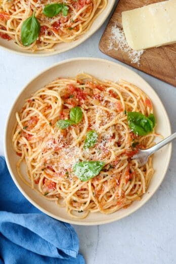 Simple pasta pomodoro recipe served in a bowl and garnished with parmesan cheese and basil.