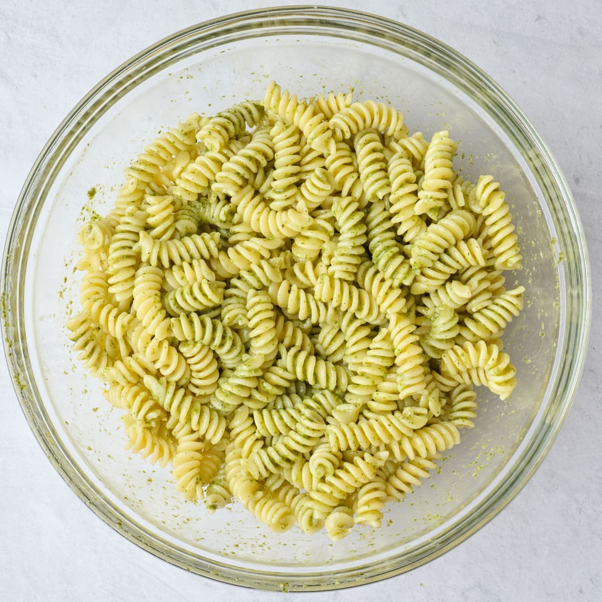 Cooked pasta in a bowl after tossing with pesto.