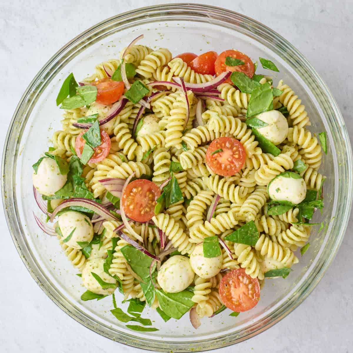 Pesto pasta salad after tossing with cheese and veggies.