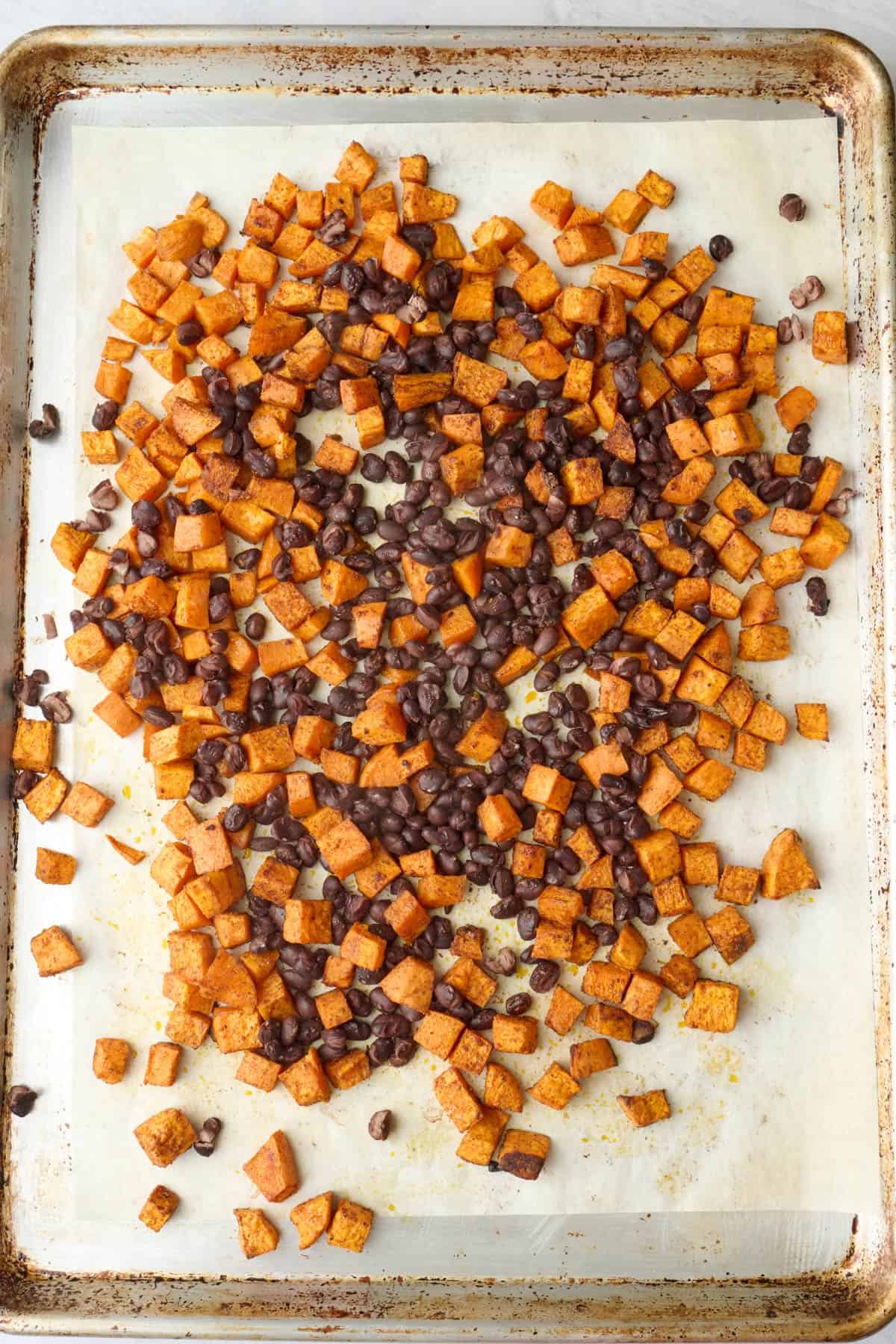 Roasted sweet potatoes with black beans added on sheet pan.
