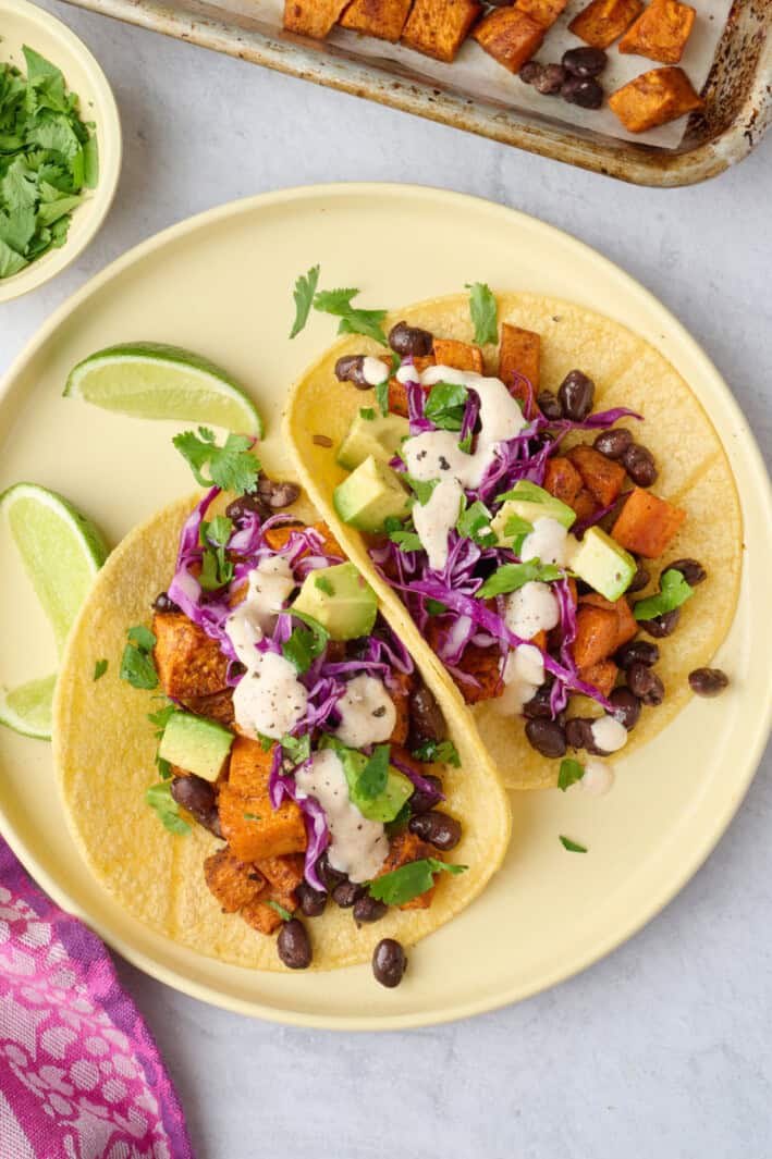 Best sweet potato tacos on a small plate with sauce lightly drizzled on top.