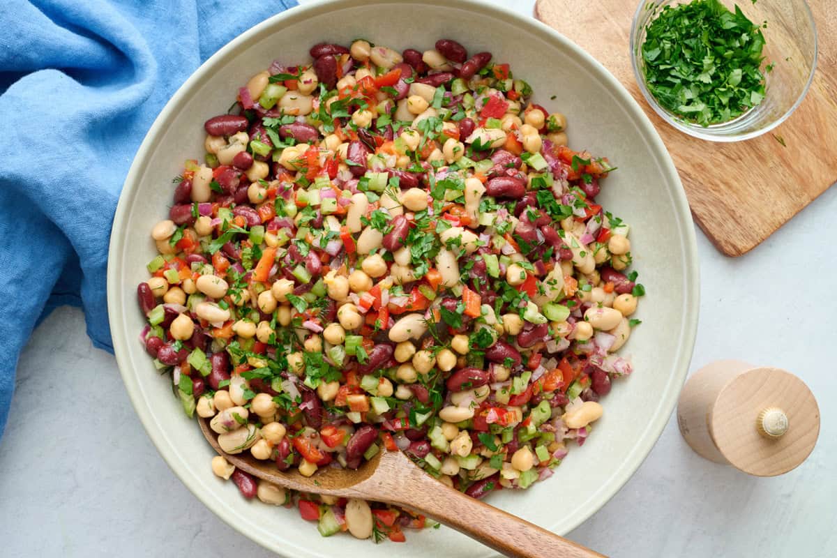 Best three bean salad in a serving dish with spoon dipped inside garnished with extra chopped parsley.
