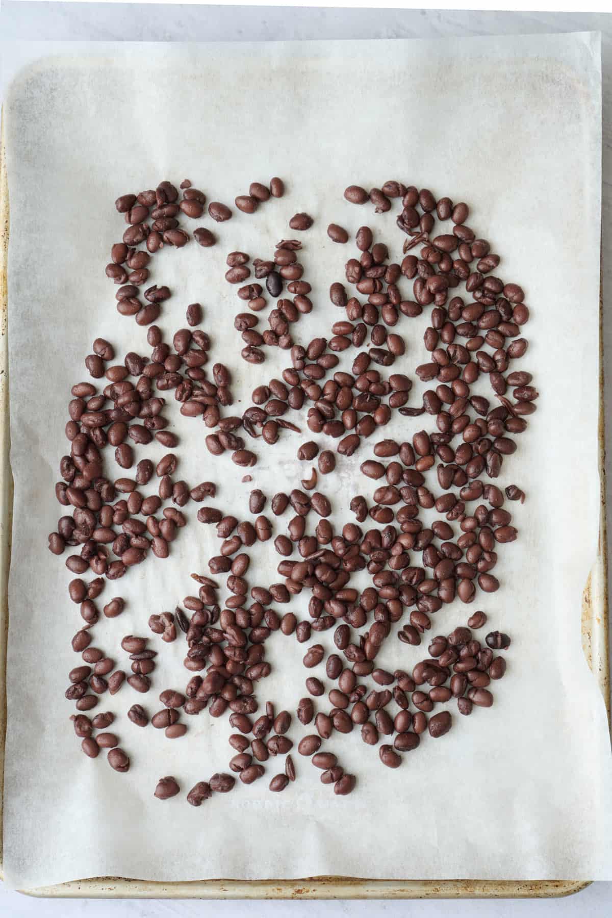 Black beans on a parchment lined sheet pan before baking.