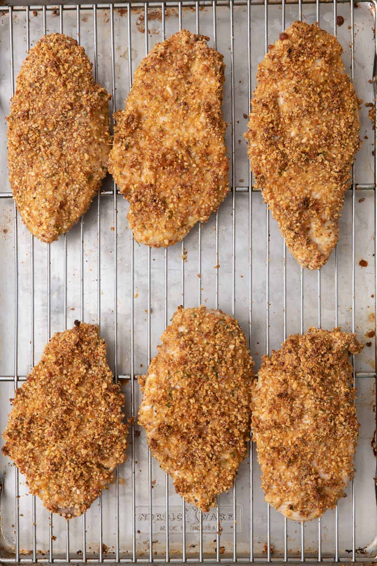 Baked almond crusted chicken cutlets on sheet pan after baking.