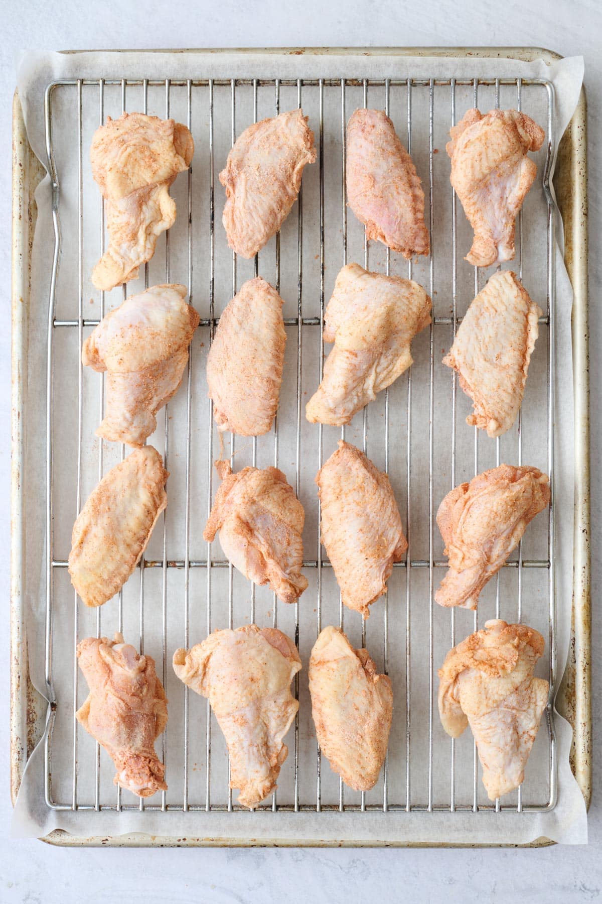 Baking powder coated wings on a wire rack on top of a baking sheet before baking.