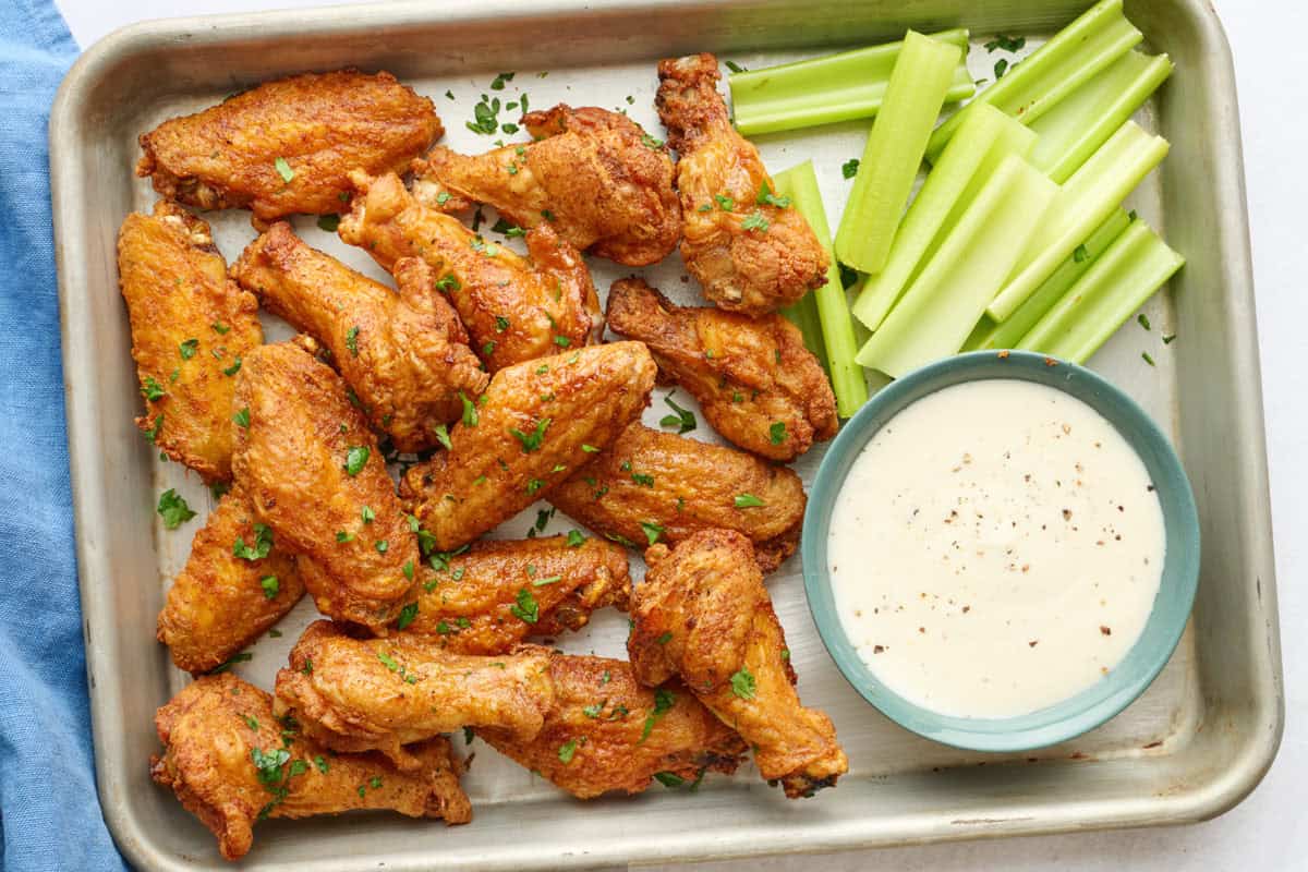 Crispy baked chicken wings and drumettes on a platter with celery and ranch for dipping.