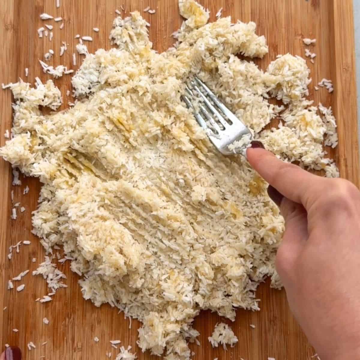 Mashing shredded coconut and banana together for cookies.
