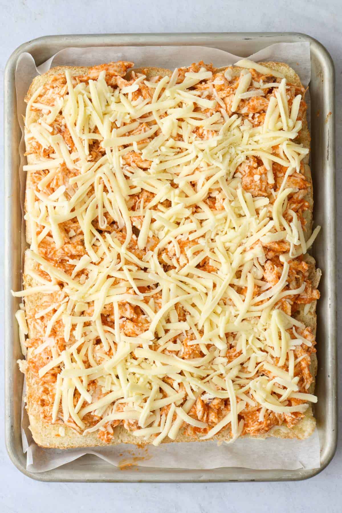 Shredded cheese sprinkled on top of shredded buffalo chicken.