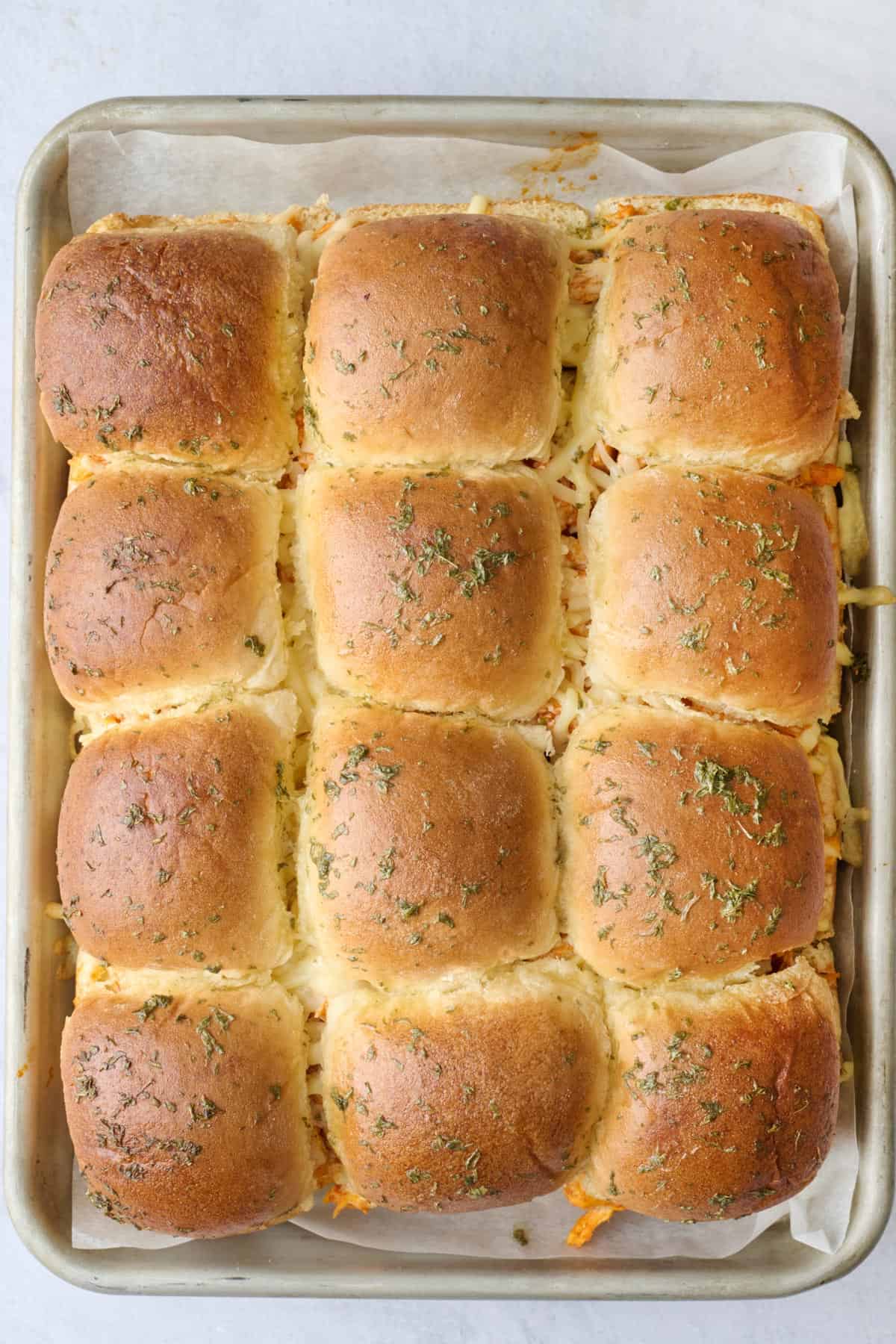 Cheesy buffalo sliders with chicken after baking showing buns golden toasted tops.