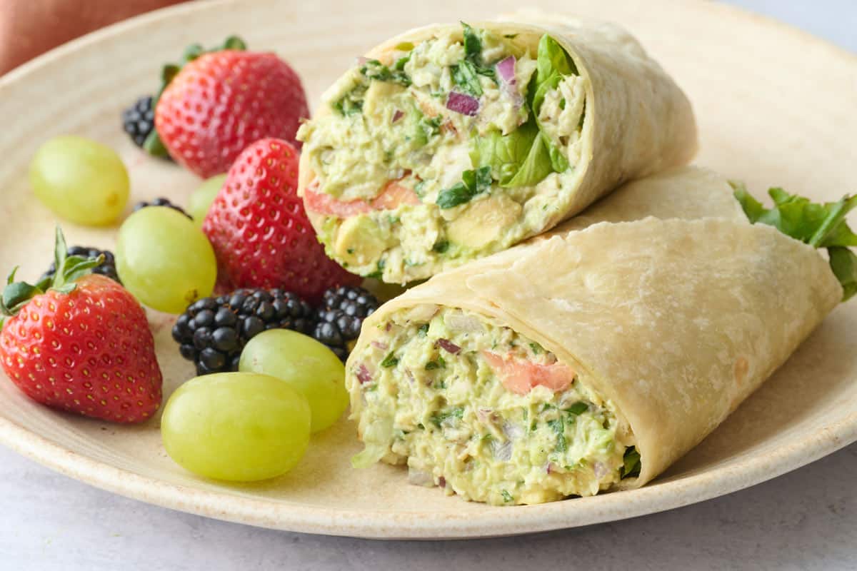 Easy chicken avocado wrap made with yogurt on a plate and served with fresh fruit.