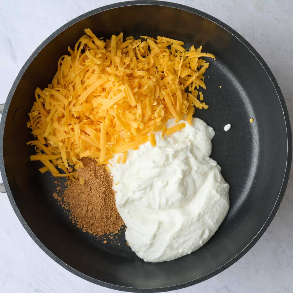 Blended cottage cheese, shredded cheddar, and taco seasoning in a small sauce pan before heating.