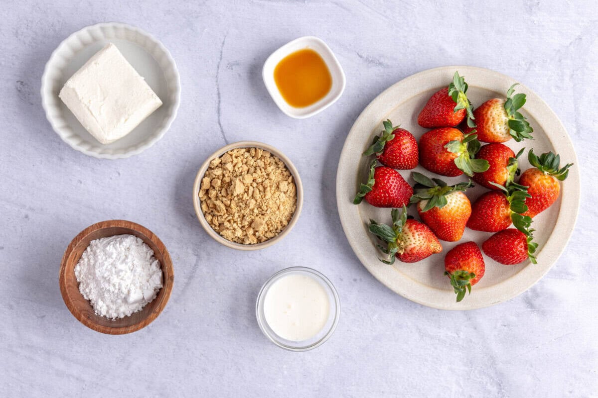 Ingredients for strawberry dessert recipe: cream cheese, powdered sugar, vanilla, heavy cream, graham crackers and fresh strawberries.