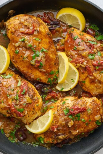 Chicken breast in a Mediterranean style sauce with sun dried tomatoes and olives garnished with lemon wedges.
