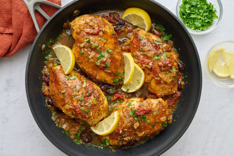 Chicken breast in a Mediterranean style sauce with sun dried tomatoes and olives garnished with lemon wedges.