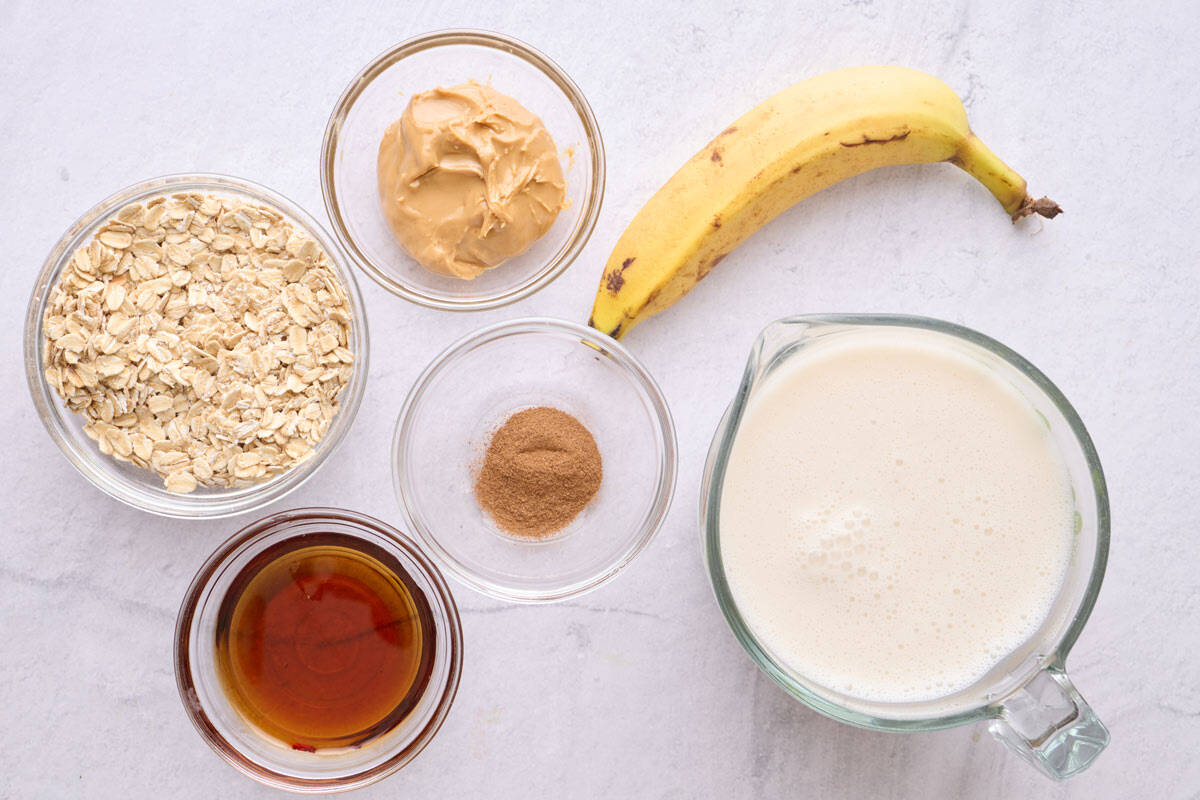 Ingredients for smoothie recipe: rolled oats, peanut butter, maple syrup, cinnamon, almond milk, and banana.