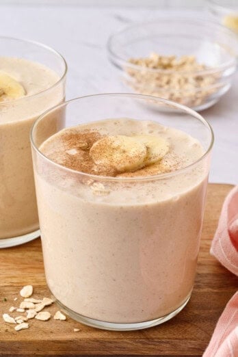 Peanut butter banana oatmeal smoothie recipe in a glass topped with cinnamon and sliced bananas.