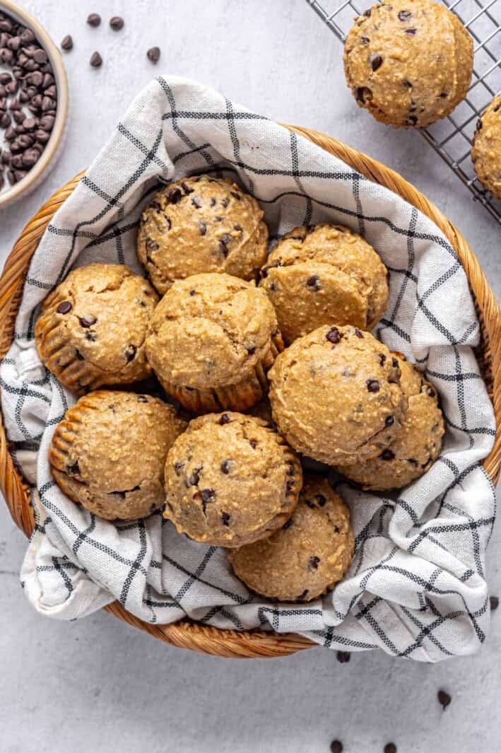 Best high protein muffins recipe in a basket with extra chocolate chips nearby.