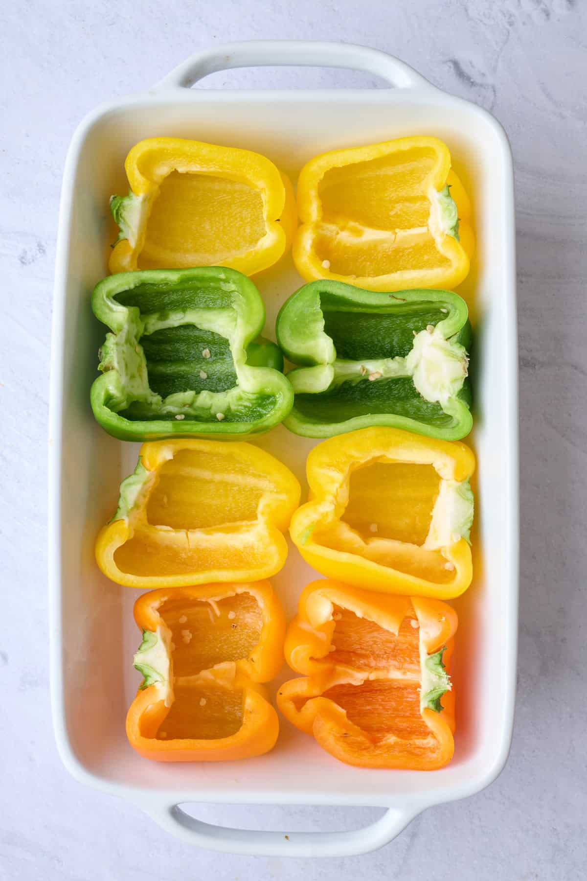 8 halved peppers in prepared baking dish with a small amount of water added.