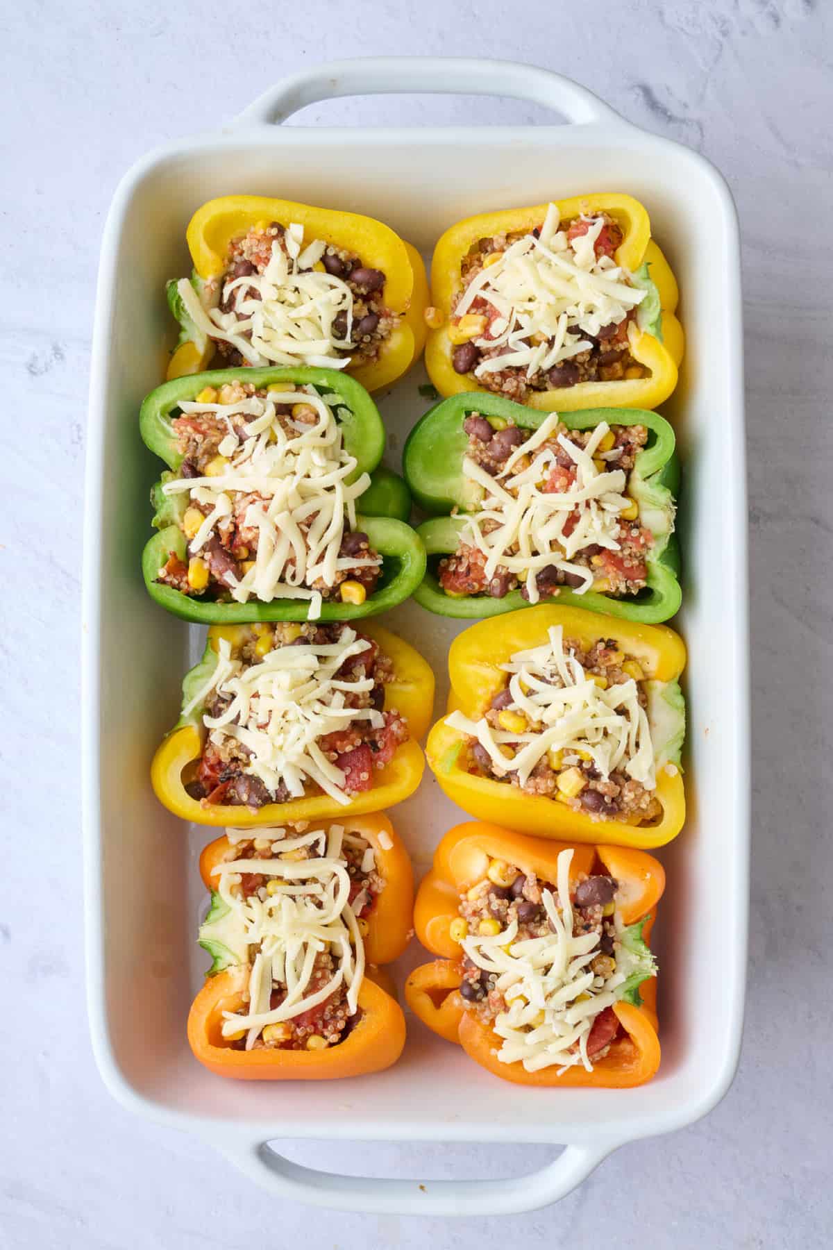 Shredded cheese sprinkled on top of vegetarian stuffed peppers.