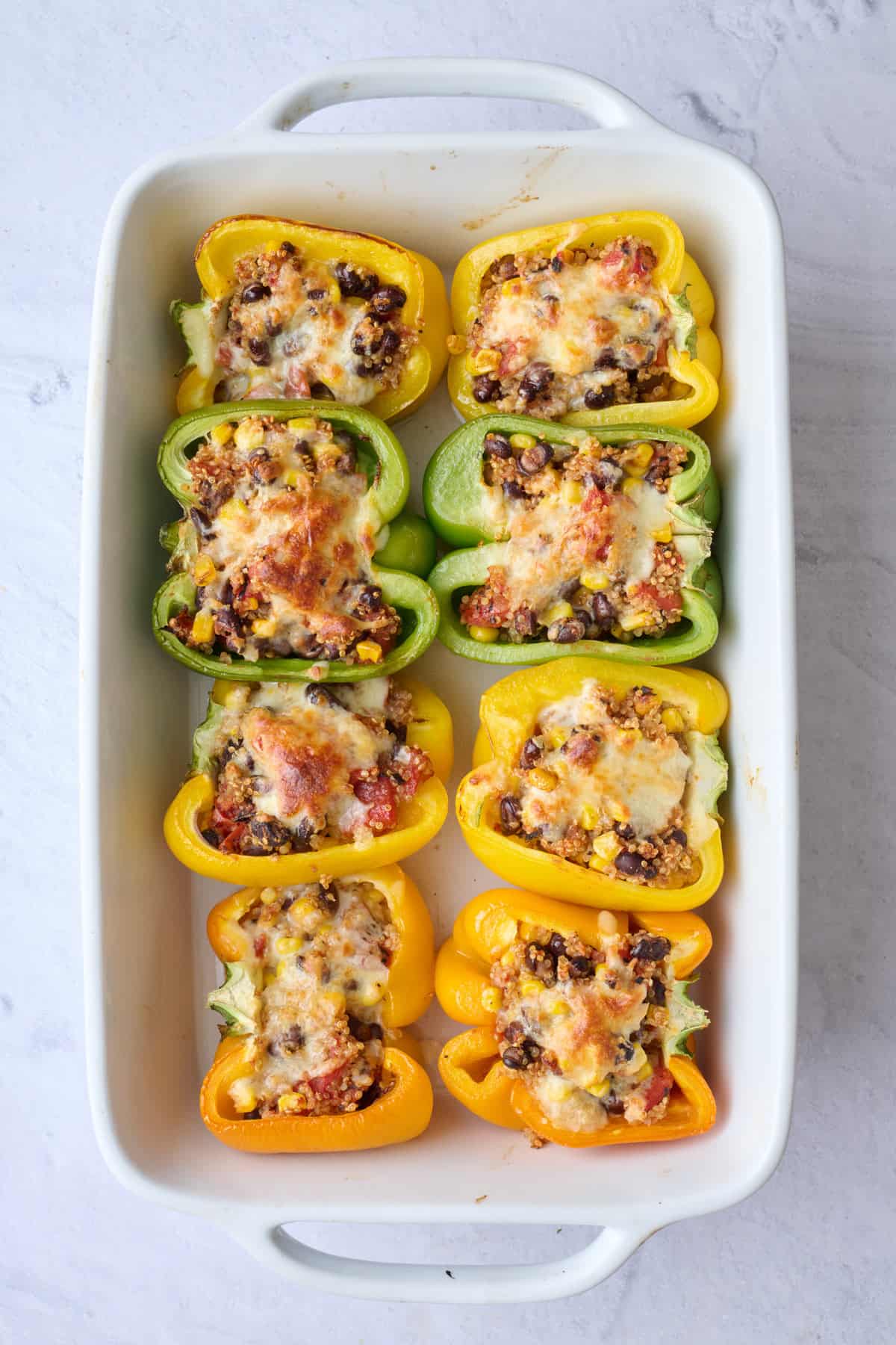 Southwest quinoa stuffed peppers after baking with melty cheese.