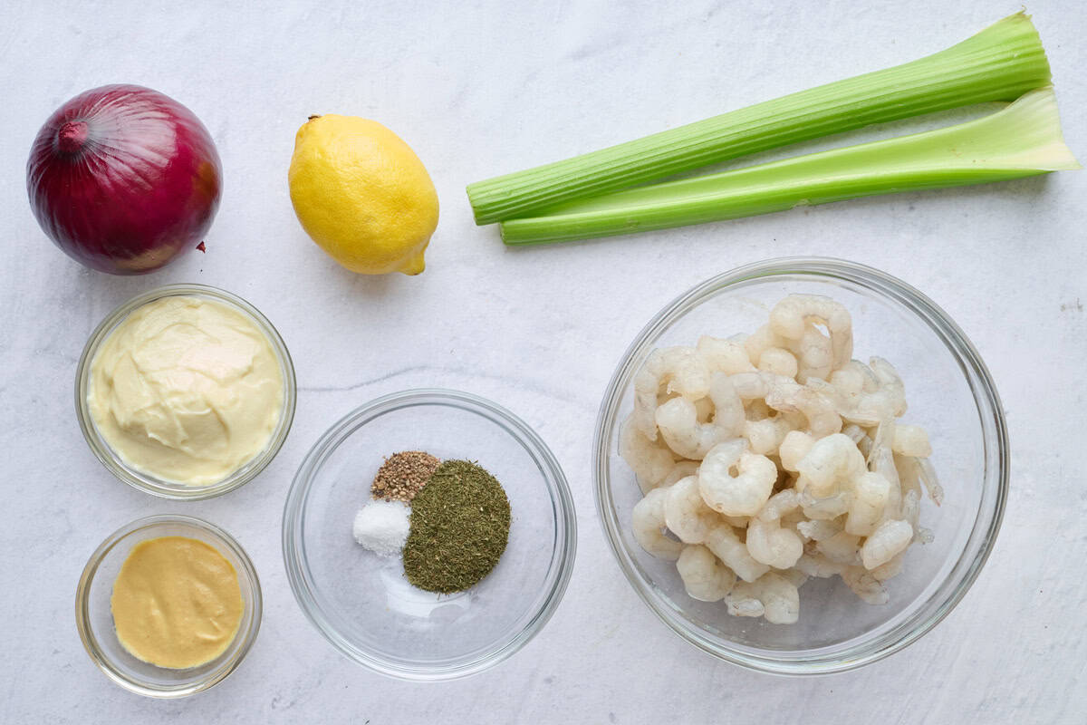 Ingredients for cold salad recipe: red onion, mayo, Dijon mustard, lemon, seasonings, shrimp, and celery.