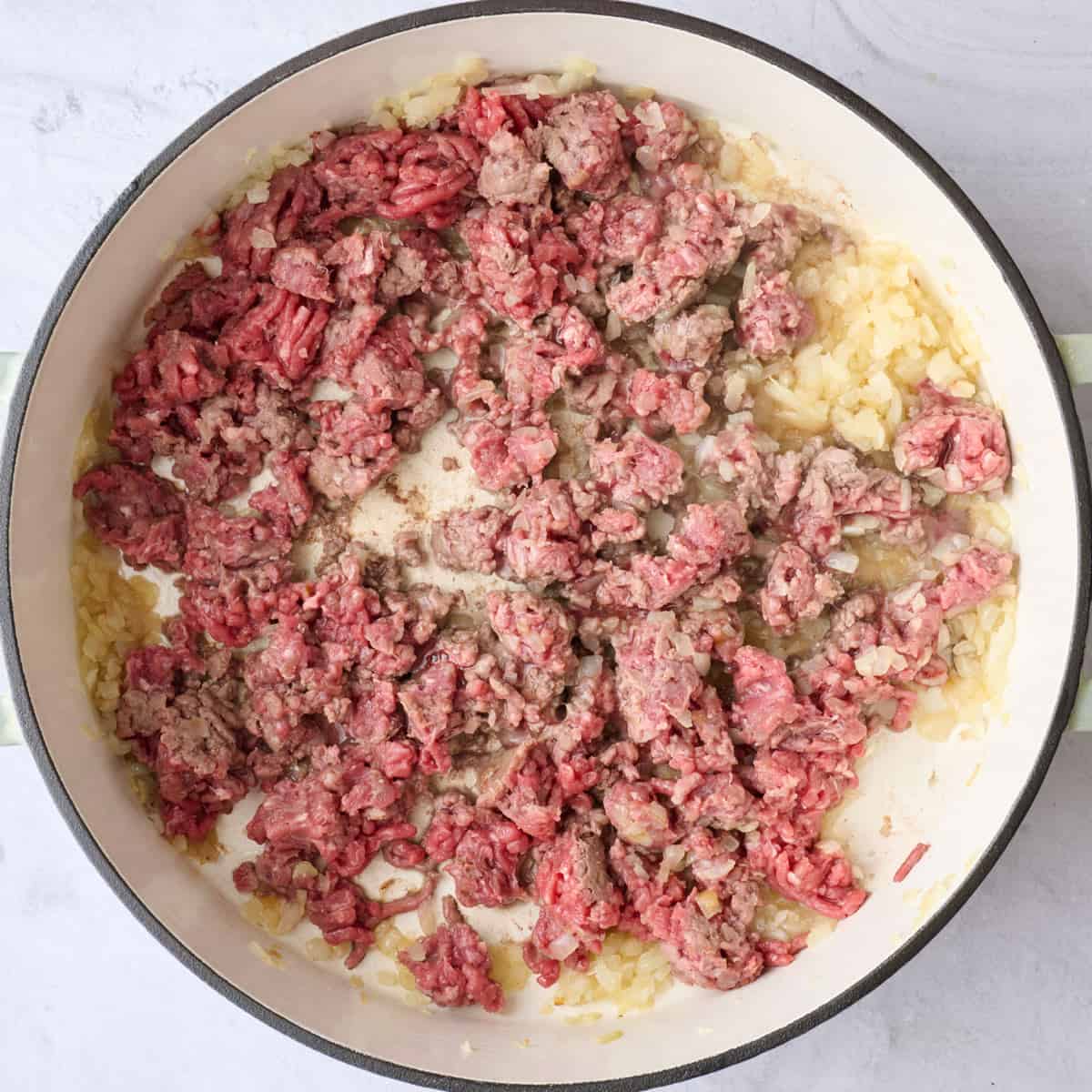 Onion in pot after cooking with ground beef added and broken into pieces before cooking through.