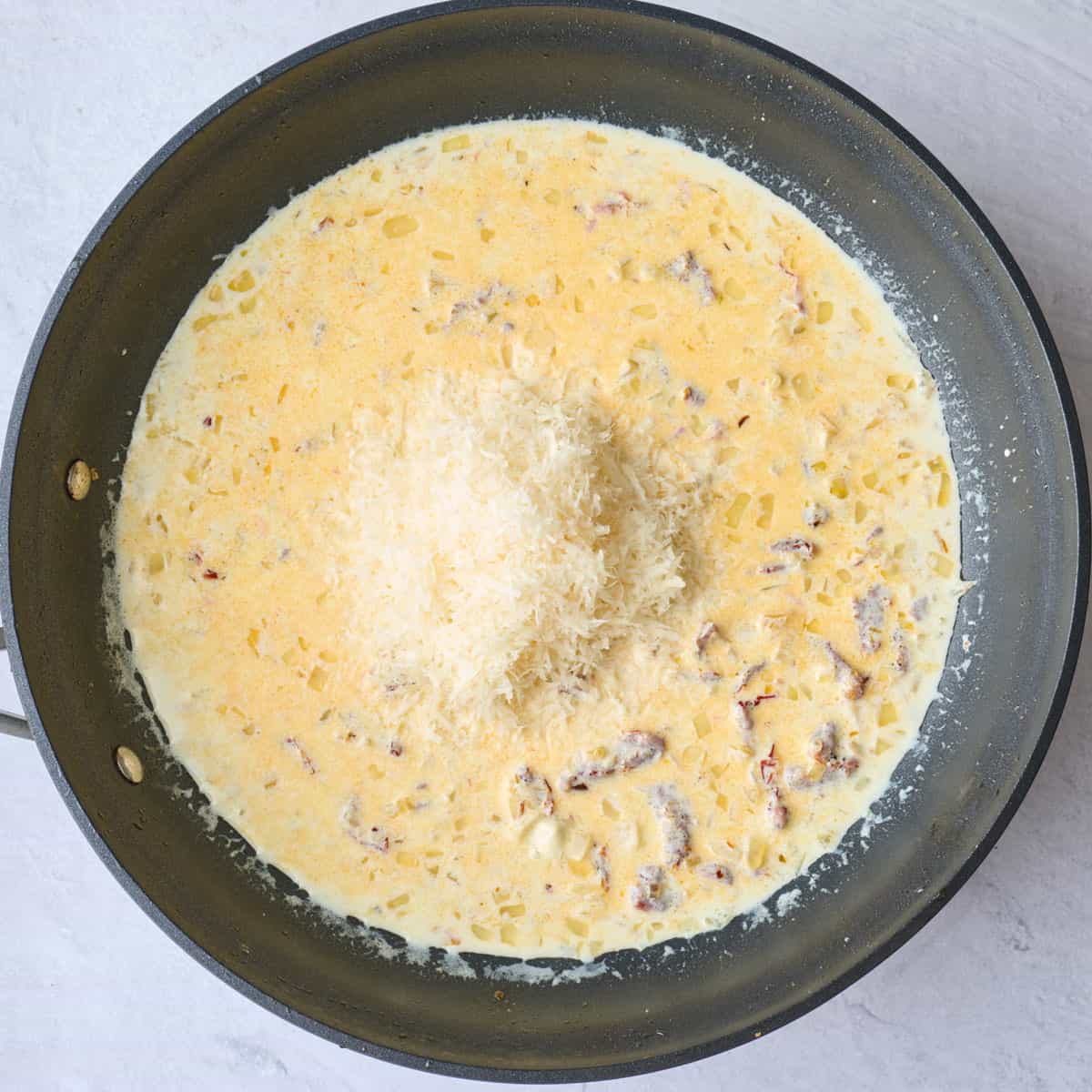 Grated parmesan added to cream sundried tomato sauce.