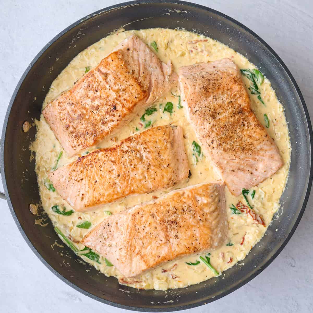 Cooked salmon filets added back to Tuscan sauce made with sun dried tomatoes and spinach.