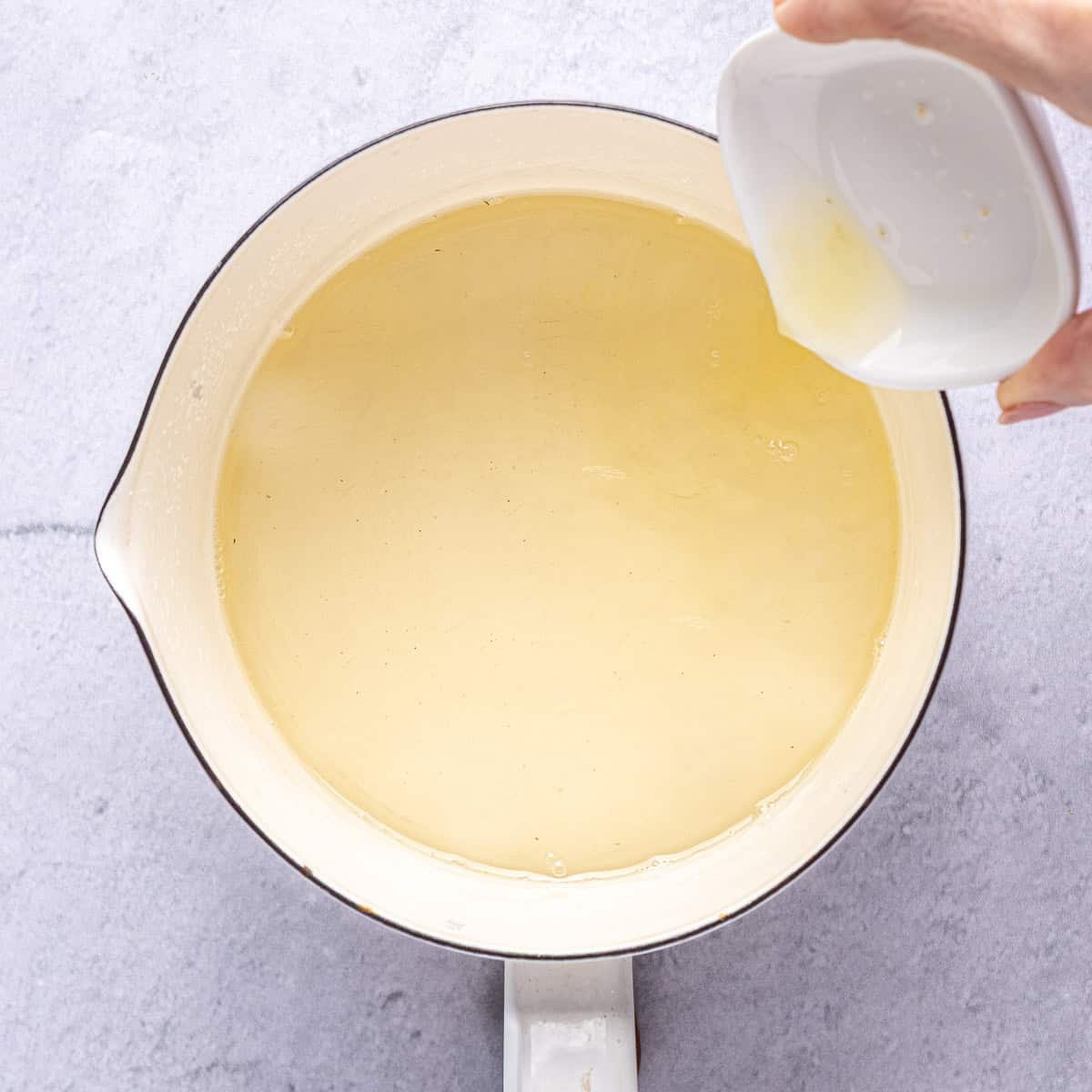 Simple syrup in pot after thickening with orange blossom water and lemon juice being added from side.