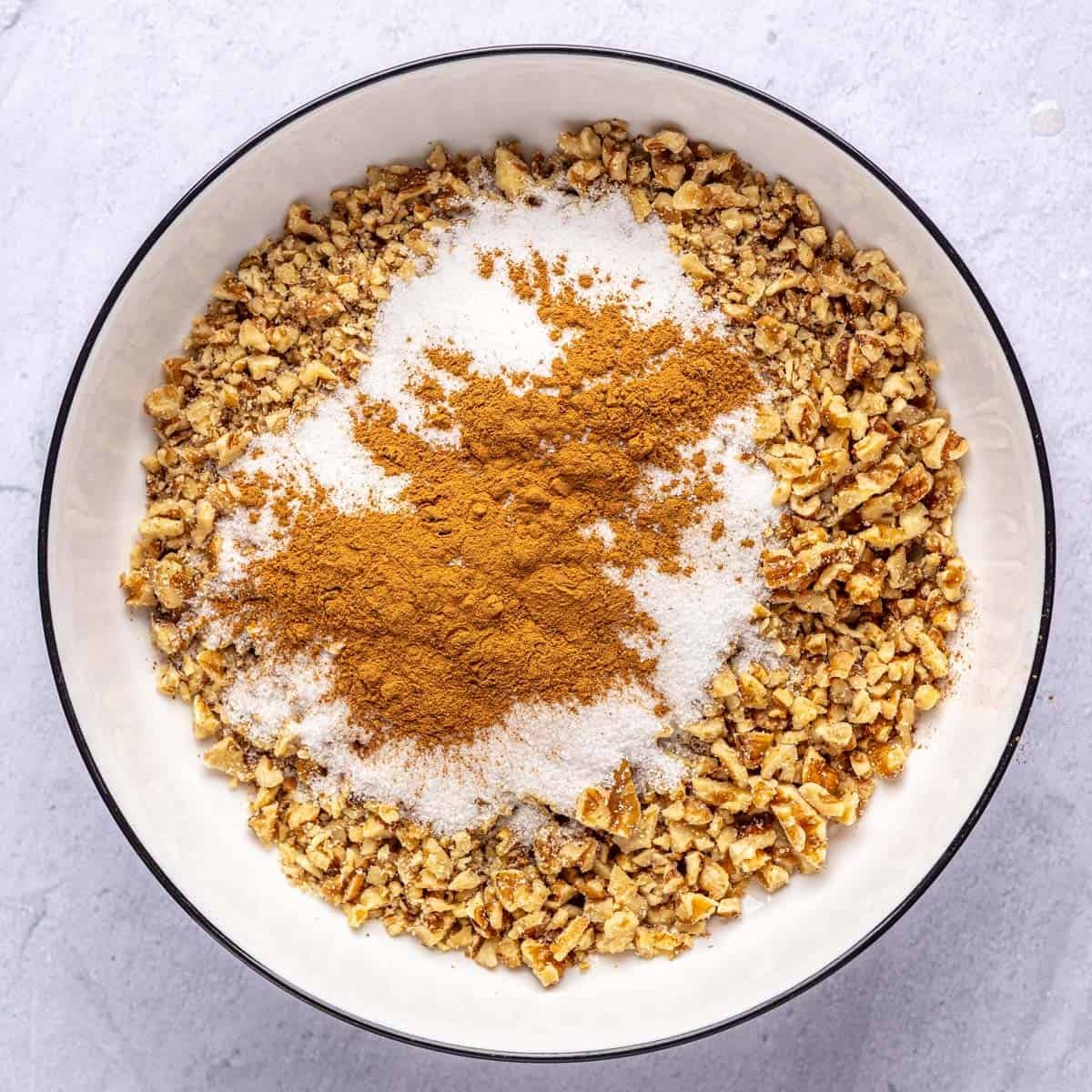 Walnuts, sugar and cinnamon in a bowl before tossing together for baklava filling.