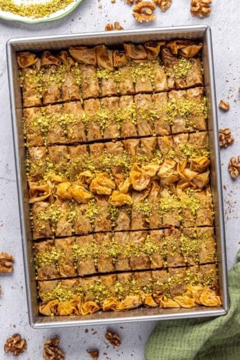 Best Baklava rolls in the baking dish garnished with crushed pistachios.